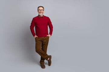 Confident Middle-Aged Man in Casual Outfit Standing Against Gray Background, Appearing Friendly and Relaxed