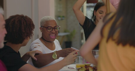 Group of friends laughing and enjoying a lively outdoor meal, emphasizing connection, celebration, and joy in a vibrant multicultural gathering under the sun