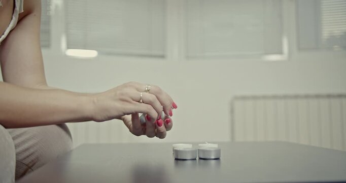A girl's hands create satisfying and calming ASMR sounds by manipulating small household tea light candles on a wooden table. The rhythmic sounds promote relaxation and focus.