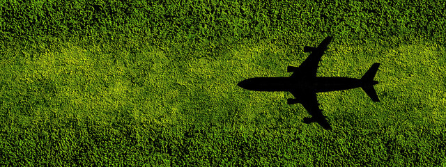 Silhouette of airplane flying over green field, symbolizing eco-friendly travel and business or vacation trips in nature. Copy space