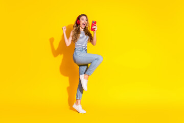 Cheerful Young Woman Listening to Music on Headphones and Celebrating with a Vibrant Expression in...