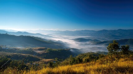 Obraz premium Stunning photo of scenic view of mountains covered in fog under a clear blue sky.