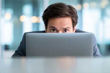 Surprised Businessman with Wide Eyes Peeking Over His Laptop