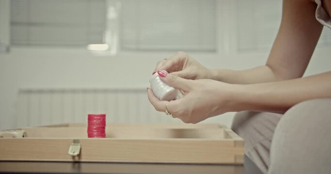 Witness a girl's hands skillfully manipulating backgammon chips, creating satisfying and distinct sounds. Her focused play brings a sense of calm and tactile enjoyment to her home environment.