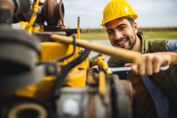 Young mechanic repairing truck and excavator engines