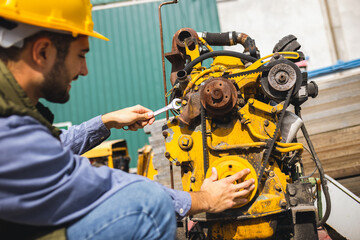 Young mechanic repairing truck and excavator engines