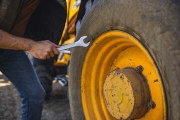 Excavator operator fixing tire on construction site