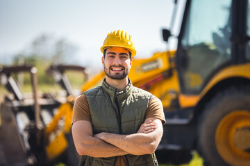 Young excavator operator standing in front of excavator