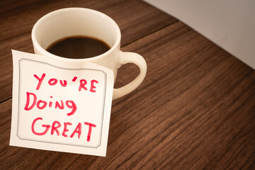A positive message on a sticky note, on a cup of coffee.