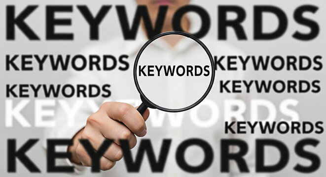 Person holding magnifying glass over the word keywords for search engine optimization and online marketing strategies to improve website visibility