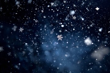 Obraz premium Delicate snowflakes drift down softly against a dark blue night sky. The scene captures the beauty of winter as flurries swirl in the cold air, enchanting viewers with its tranquility