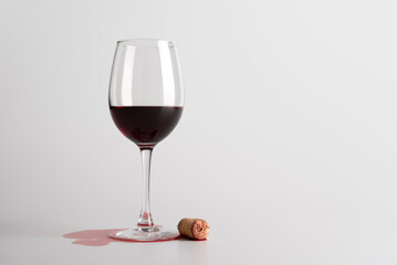 Spilled Red Wine Glass with Cork on White Background
