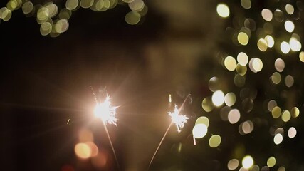 Happy New Year! Burning sparklers in hands on background of christmas tree golden lights and fireplace at night. Glowing fireworks in hands, new year eve holiday celebration footage
