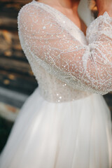 Close-up of a wedding dress with lace sleeve decorated with beads and sequins. Delicate embroidery highlights elegance and fine craftsmanship.