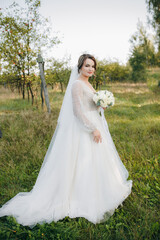 Bride in a white wedding dress standing in a garden, holding a bouquet of white roses. Warm sunlight creates a romantic atmosphere full of tenderness and serenity.