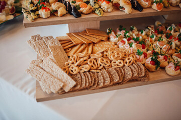 Elegant catering buffet table with assorted gourmet appetizers and canapés, decorated with salmon, red caviar, herbs, and cheese. Festive party or wedding reception food arrangement.