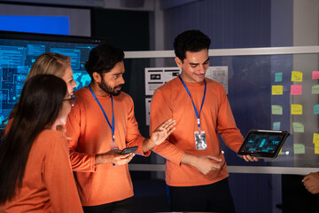 Diverse team of IT security experts reviewing digital data on a tablet in a meeting control room. Colleague presents a successful solution. UX, UI mobile app design, new software development