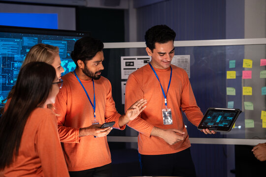 Diverse team of IT security experts reviewing digital data on a tablet in a meeting control room. Colleague presents a successful solution. UX, UI mobile app design, new software development - Powered by Adobe