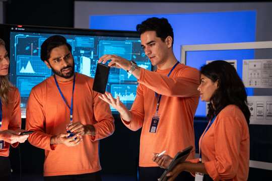 Creative designer showing mobile to diverse tech team to analyzing design and review app development in a high-tech security room. Planning strategy and discussing of cybersecurity - Powered by Adobe