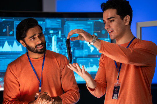 Creative designer showing mobile to professional tech team to analyzing design and review app development in a high-tech security room. Planning strategy and discussing of cybersecurity