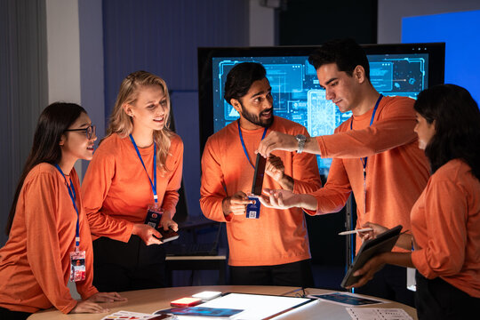 Happy diverse team showing success product to colleagues. They are collaborating while reviewing digital concepts on a smartphone, successful teamwork, technology innovation in the meeting