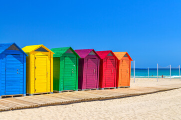 Playa de San Juan beach in Alicante city, wooden colorful storage huts sheds cabins for sports equipment on sandy beach of Mediterranean Sea coast Costa Blanca coastline in sunny summer day, Spain