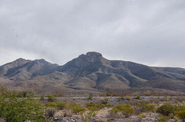 Explore rugged desert landscapes beneath a cloudy sky with mountains in the distance ideal for travel, adventure, and outdoor lifestyle projects