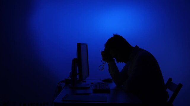 Stressed man experiencing burnout working late at computer