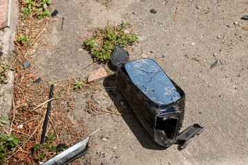Broken side mirror of a car after a traffic accident. Pieces of shattered glass reflect the street....