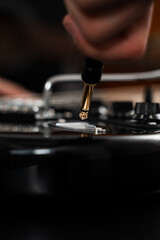 Jack cable is plugged into the black electric guitar, activating its signal path for rich tones and stage-ready sound. Plugging Cable into Electric Guitar close-up.