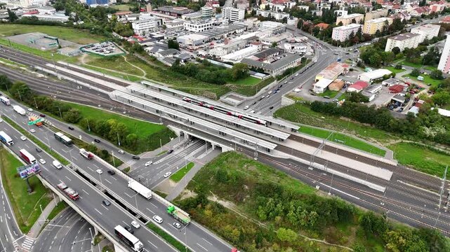 Aerial drone view of a train stopped on a bridge above dense urban traffic at night, with glowing lights and steel lines emphasizing tension, scale, and the rhythm of modern transport systems.