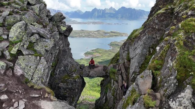 4K Drone shot - Drone passing by the devils door while a man is sitting down on the rock arch with amazing views