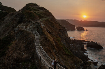 A couple visits the O FUciño do Porco viewpoint in O Vicedo at sunset. Galician coast, Galicia.