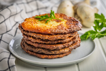 Fried potato pancakes on plate on white table.