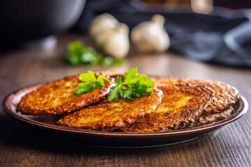 Fried potato pancake on plate on wooden table.