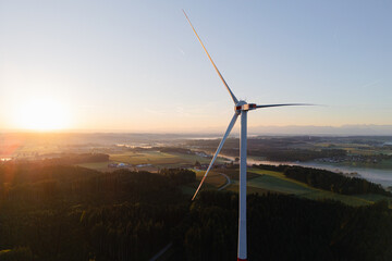 Wind Turbine at Sunrise Over Forest and Farmland