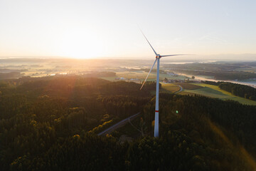 Wind Turbine at Sunrise Over Forest and Farmland