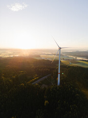 Wind Turbine at Sunrise Over Forest and Farmland