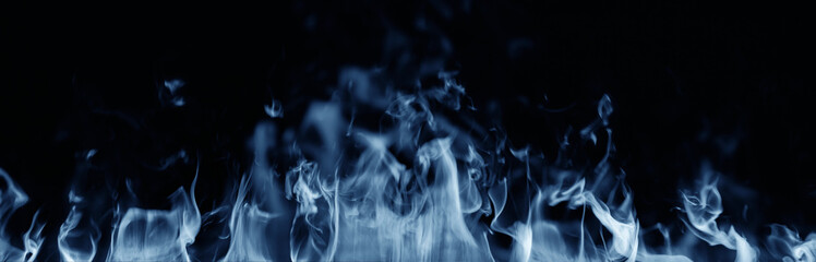 Dynamic bright blue flames isolated on dark black background — close-up view of burning fire...