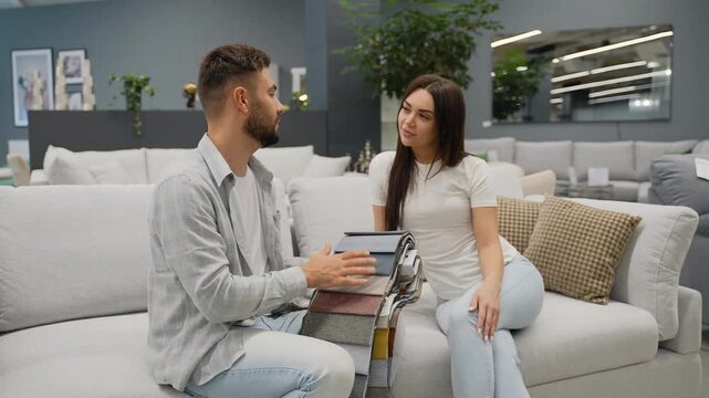 Just married couple choosing fabric color sample for sofa in furniture store