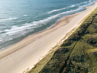 Aerial View of Serene Coastal Beach with Ocean Waves and Grassy Terrain