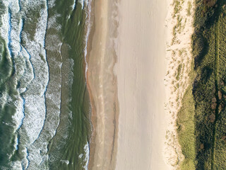 Aerial View of Serene Coastal Beach with Ocean Waves and Grassy Terrain
