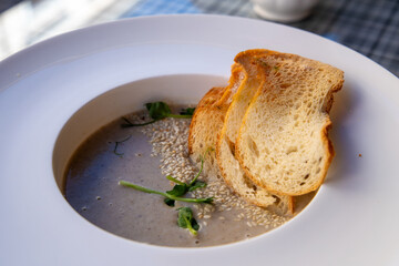 Champignon mushroom soup with bread croutons and fresh mushrooms in a white bowl. A seasonal autumn cream soup. Vegetarian. Copy space.