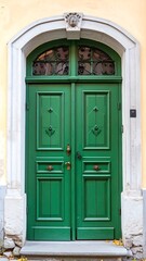 Green double doors, arched entryway, light beige wall