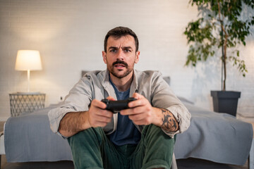 Young man intensely playing video game with controller