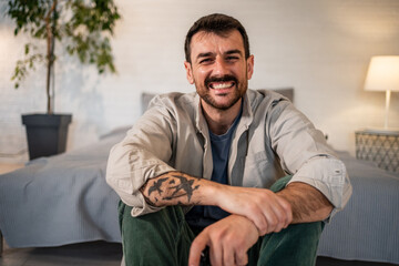 Fototapeta premium Young man smiling, relaxing at home, looking at camera