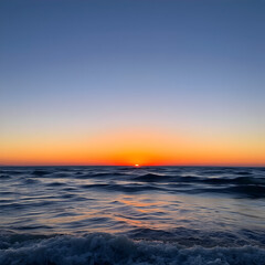 Obraz premium Serene Ocean Sunset with Gentle Waves and Clear Sky