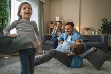 Fototapeta premium Family enjoying playful pillow fight in living room