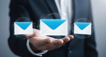 Professional businessman presents modern digital communication with glowing email icons floating above his hand, symbolizing connectivity and data exchange.