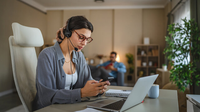 Woman working from home using headset and laptop